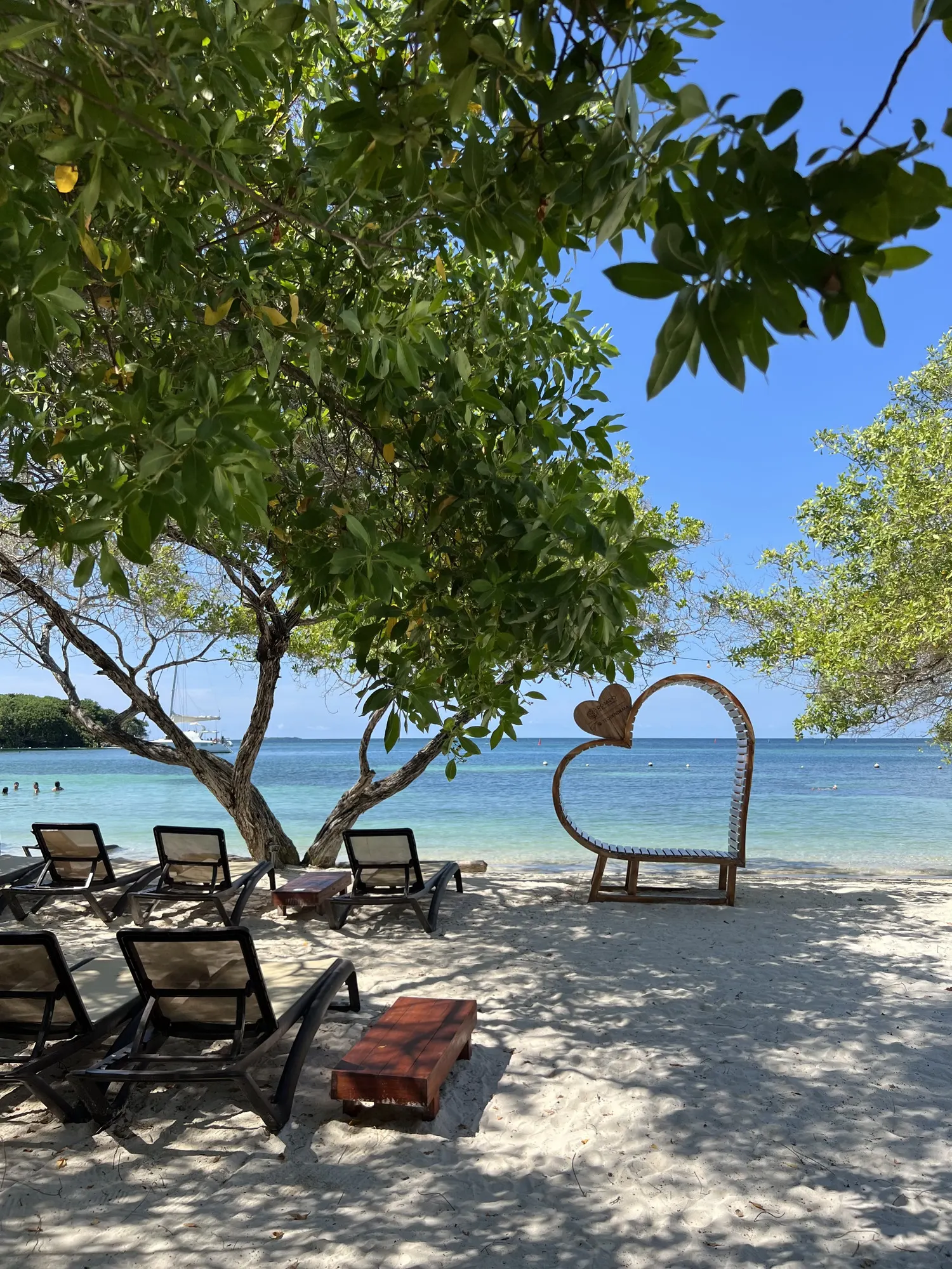 Heart-shaped swing and loungers under a tree
