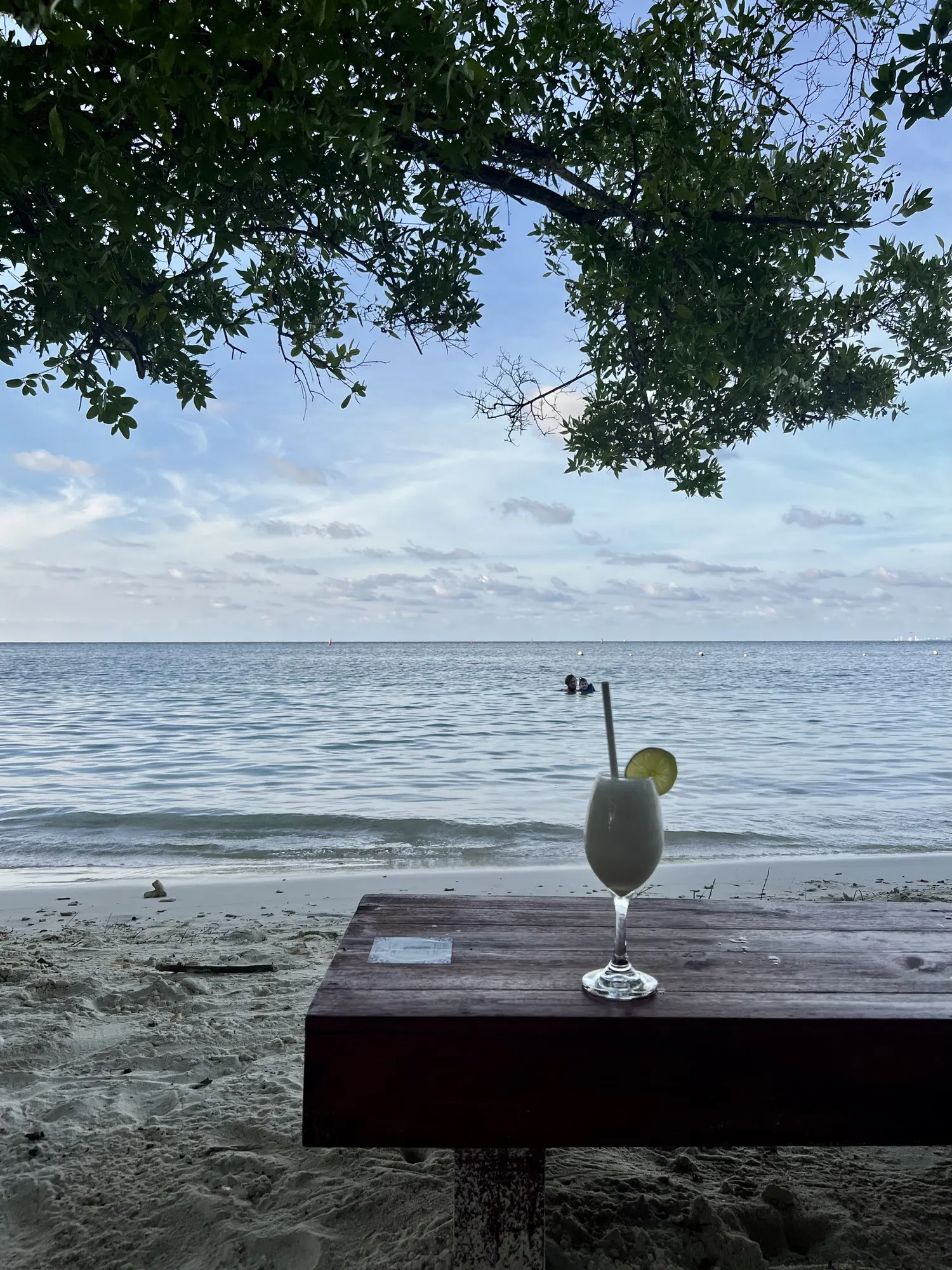 One cocktail on a beach table, sea to the horizon