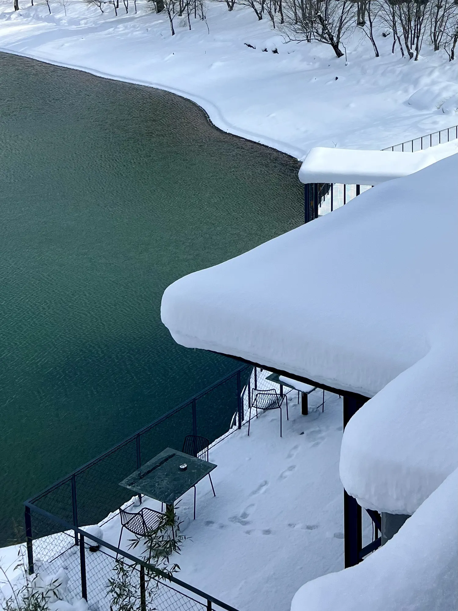 A snowy terrace above the green water