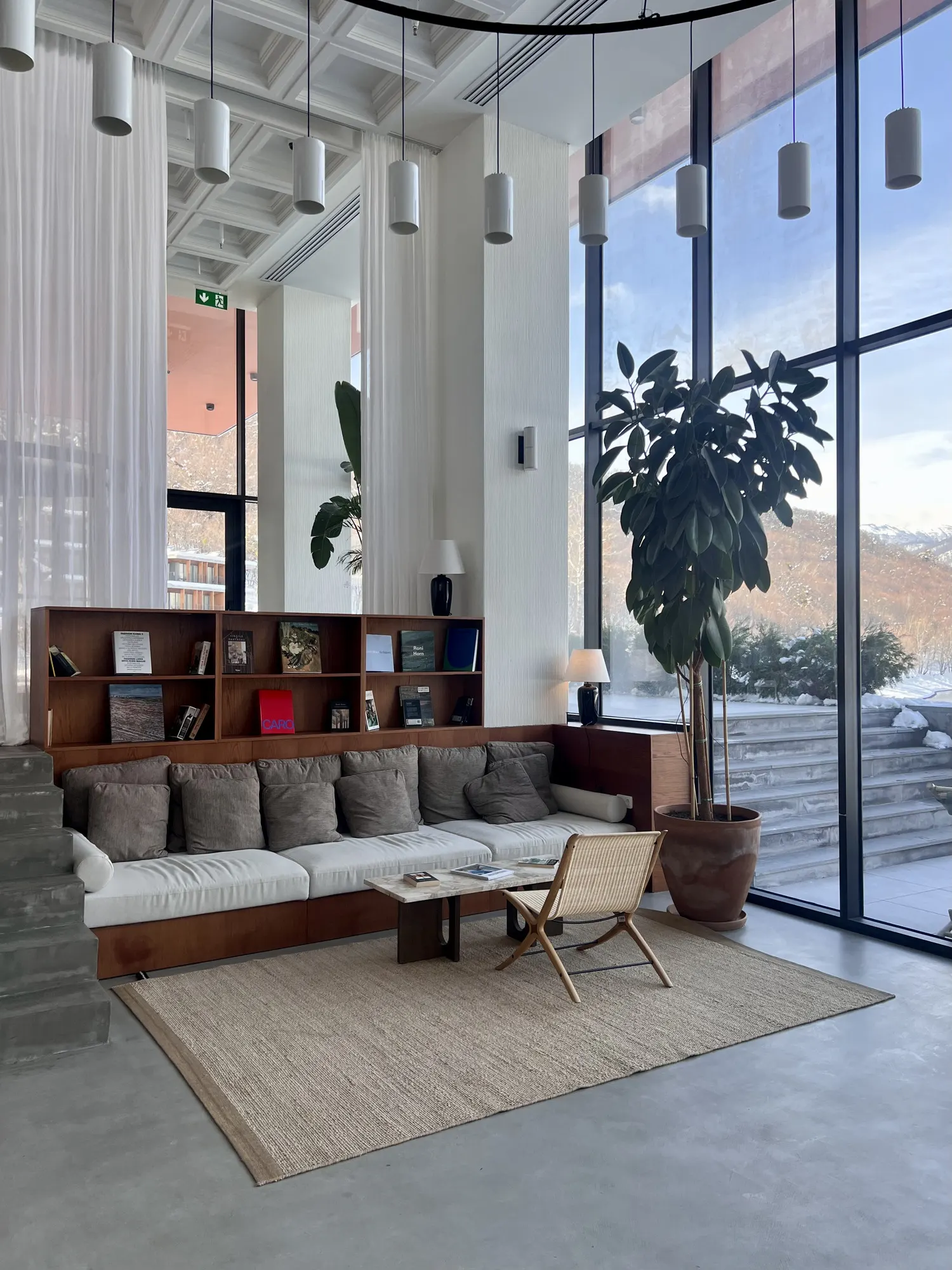 A sofa and books under a double-height window