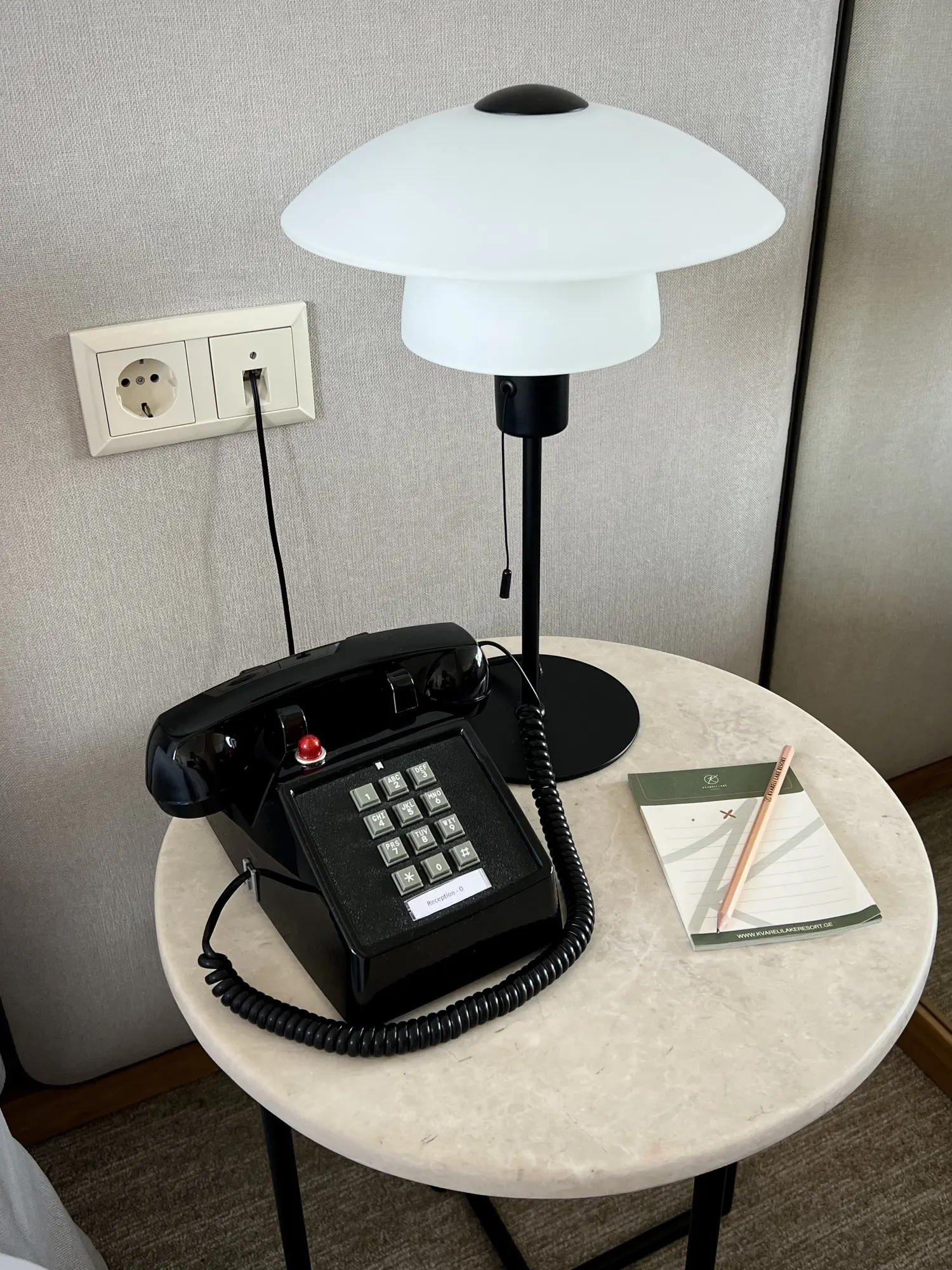 Black desk phone and a lamp by the bed